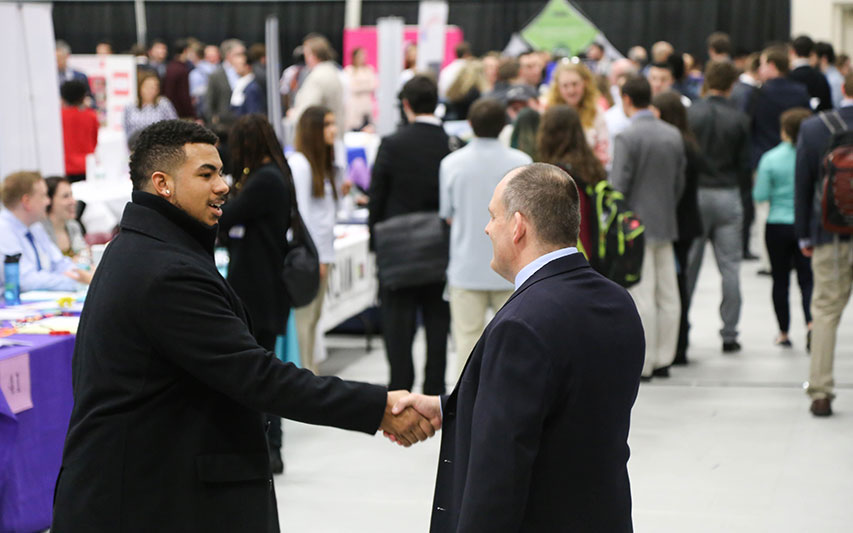 Student shakes hand of employer at Career and Internship Fair