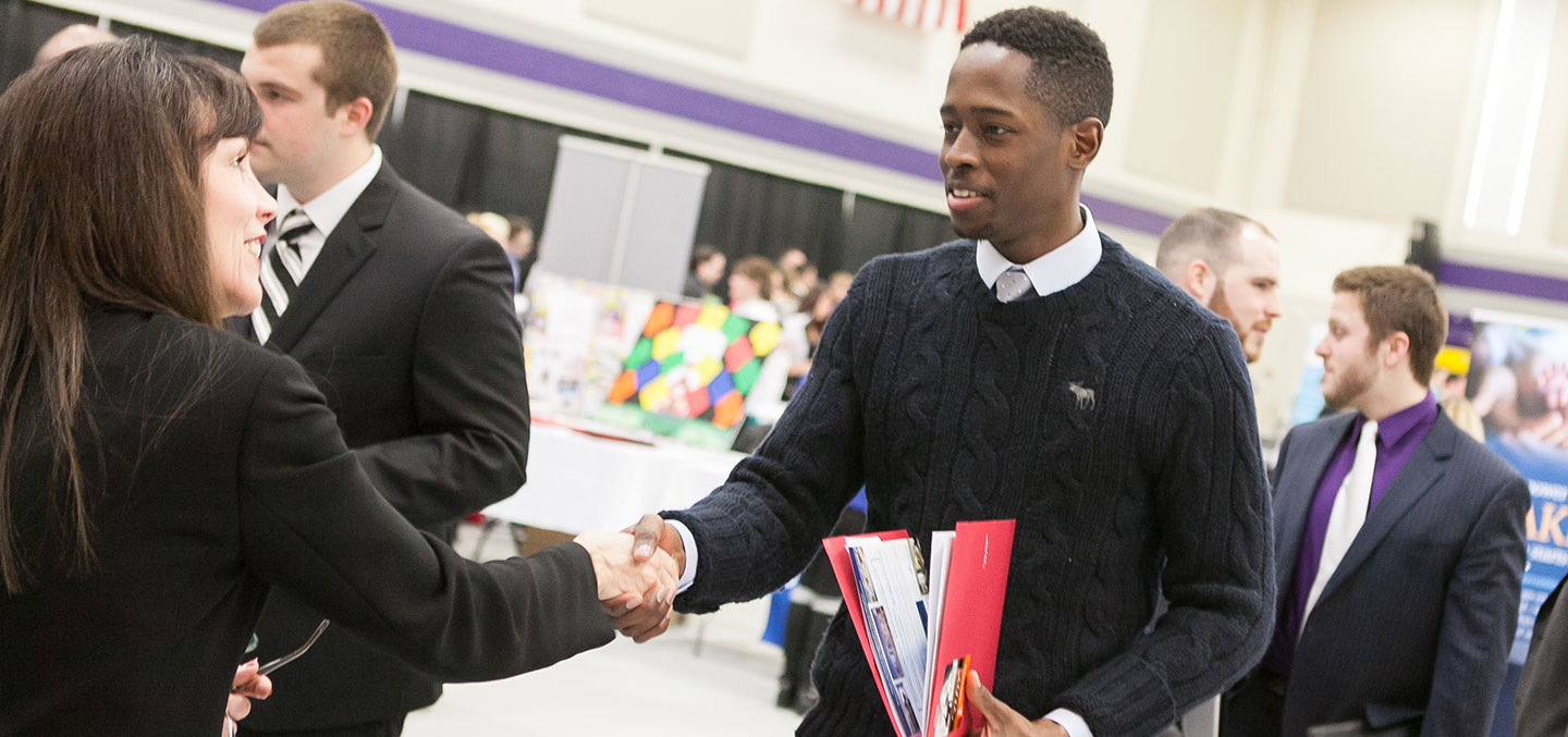 A Curry College Center for Career Development Employer partner shakes the hand of a current student