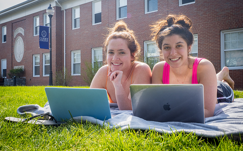 Students at laptops on the Quad sign up for a summer course at Curry College