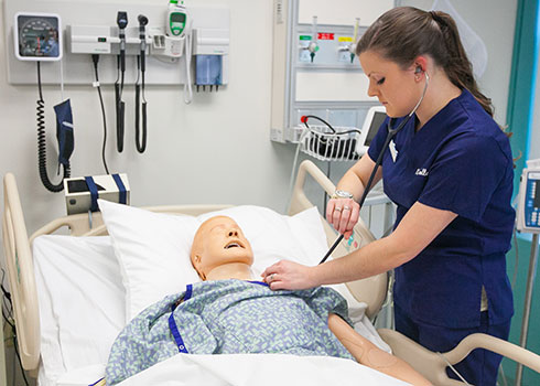 Curry College Master of Education (M.Ed.) student checks vitals of a SIM patient