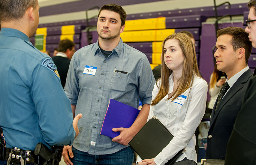 Students pursuing a criminal justice degree at Curry College listen intently to a State Police Officer