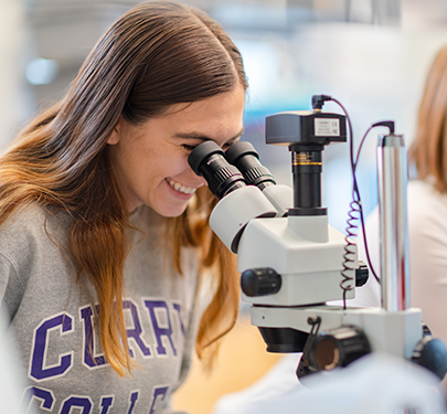 A student looks through a microscope in the Curry College science lab