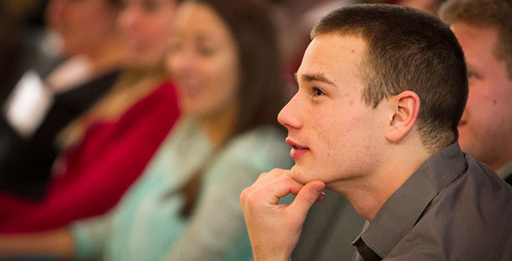 A Curry College student, representing the need for support, smiles in class