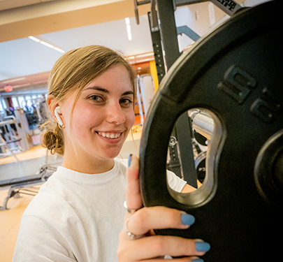 Student adds weight to her barbell at the Fitness Center