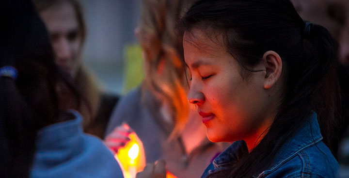 A student attends a candle light vigil