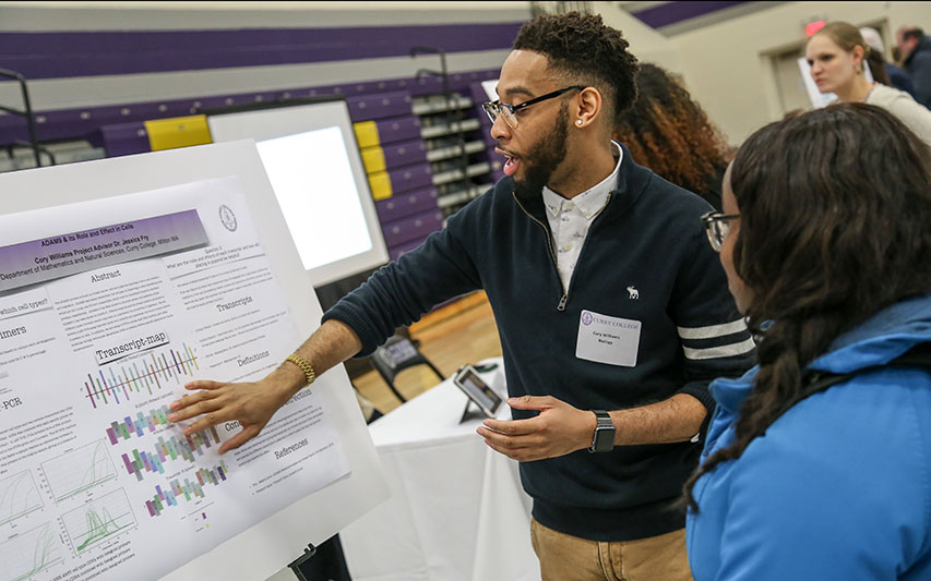 A student presents to a peer at the Curry College Academic Forum