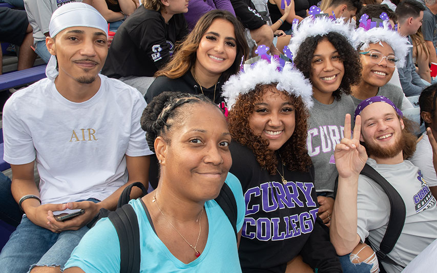 Fans in the football stands at Curry College Homecoming and Family Weekend