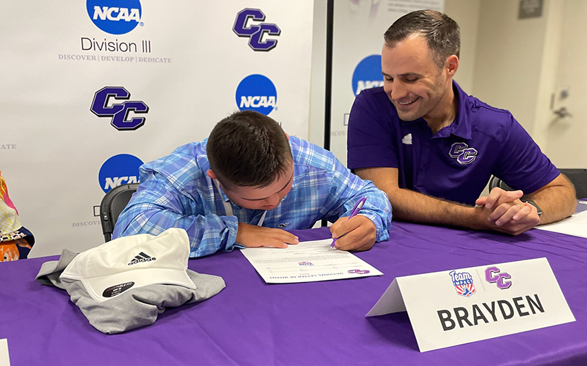 Brayden Gero of Team IMPACT signs letter of intent next to Head Coach Pete Roundy