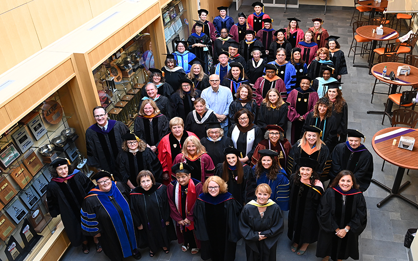 Faculty members pose in the Hall of Champions during academic Convocation 