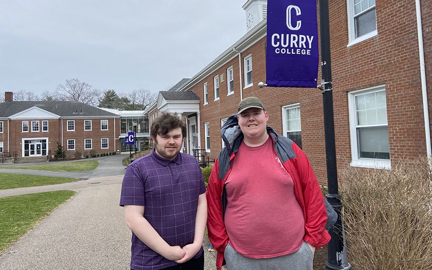 Two students post in academic quad