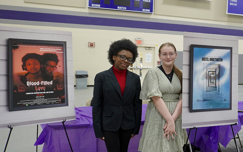 Graphic Design students pose in front of projects