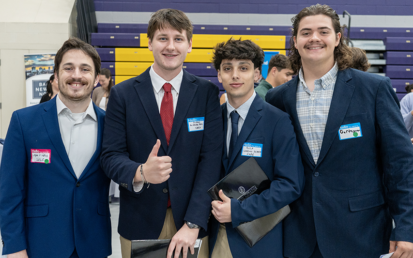 4 male Curry students dressed in business attire at the Business & Technology Career Fair