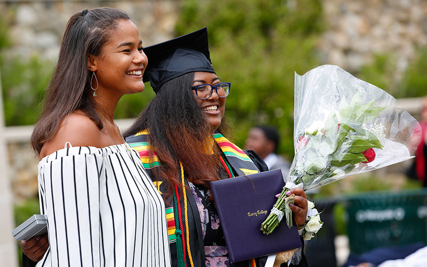 A Curry College graduate smiles for a photo with her family member at Commencement