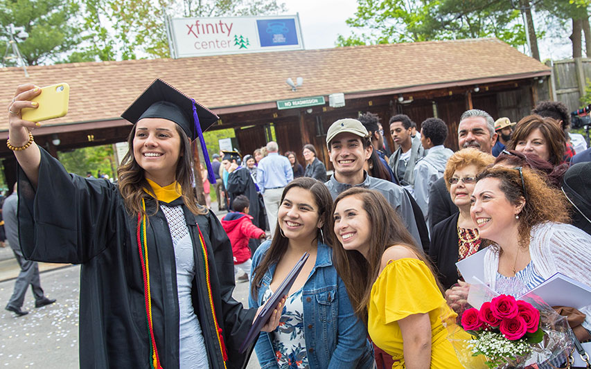 A Curry College graduate smiles for a photo with her entire family at Commencement