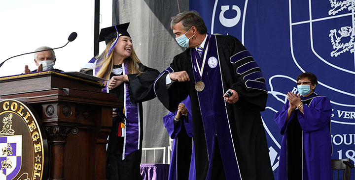 Miranda Treible '20 elbow bumps Curry President Kenneth K. Quigley, Jr. after singing the National Anthem