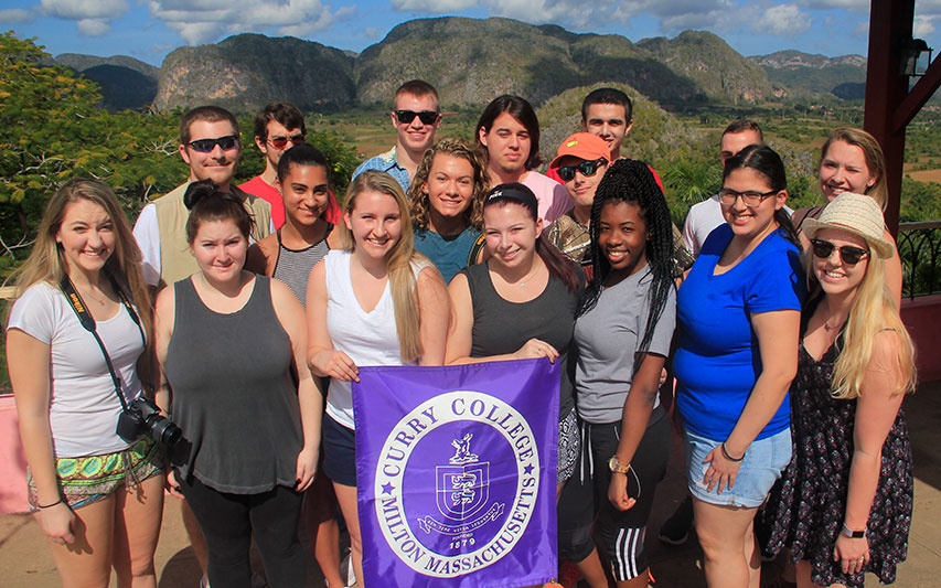 Students on Cuba study abroad trip pose for a photo with Curry College banner.