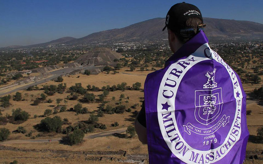 Curry College student in Mexico with College banner.