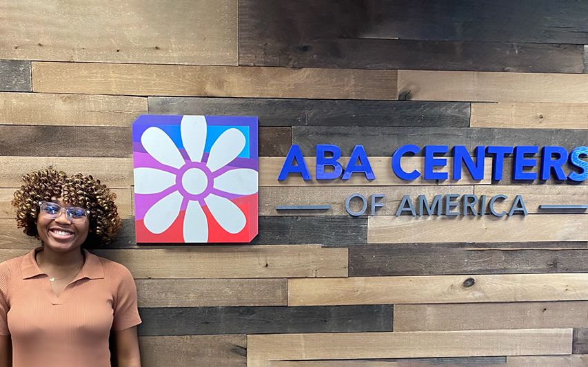 Sarah Izidore Poses in Front of ABA Centers of America Sign