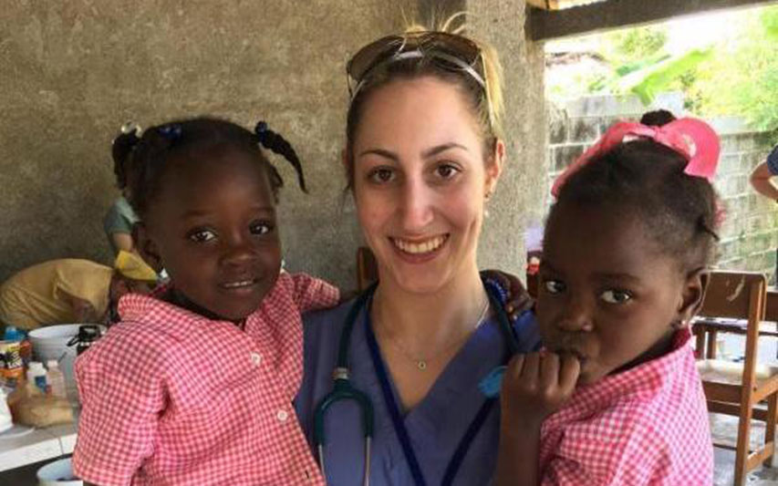 School of Nursing alumna Katie LeBlond '16 poses with two children in Haiti, while on a medical mission trip.