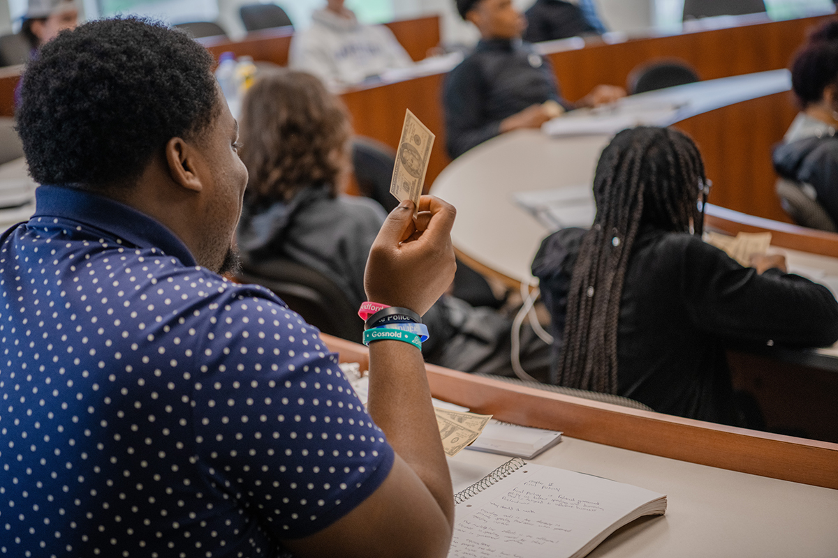 Student holds up money in macroeconomics class