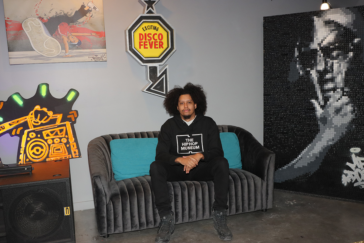 Kylerr Bucano sits on couch inside room with rap artist posters