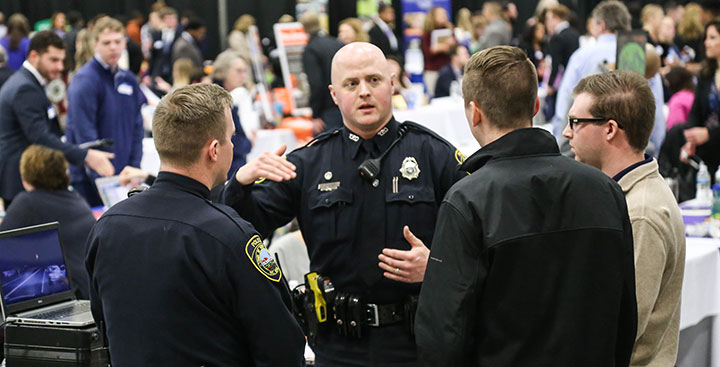 Students listen to a police officer speak at the Curry College Center for Career Development internship and career fair