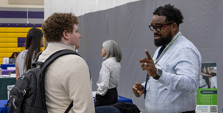 An employer partner networks with a current student at a recent job fair