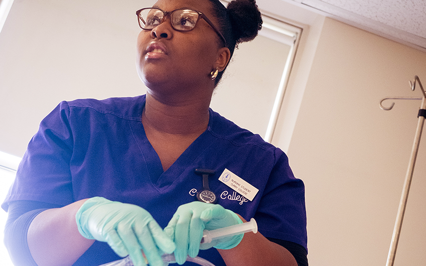 A Curry College nursing student works in the simulation lab
