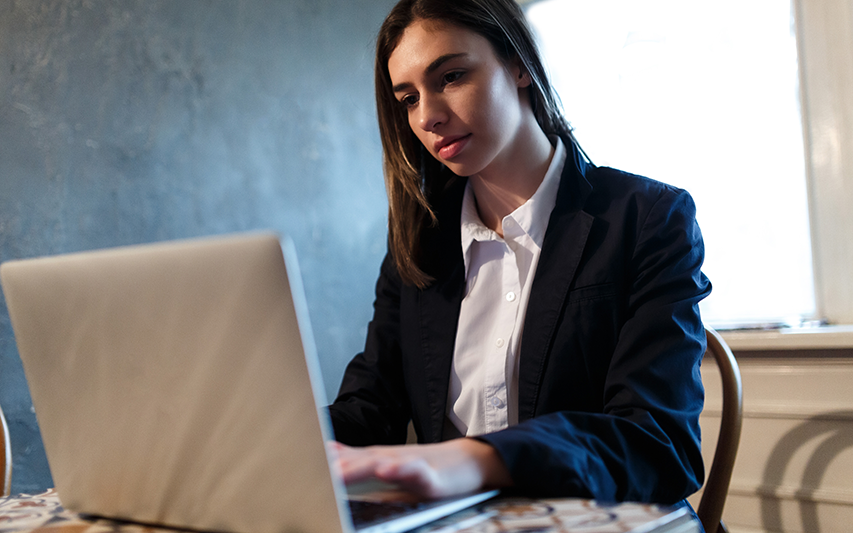 A student pursuing a Curry College Master of Arts in Criminal Justice Degree on her laptop