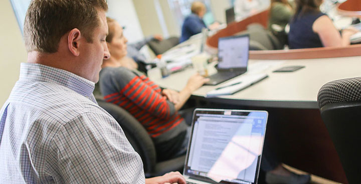 Curry College continuing education accounting student on his laptop in class