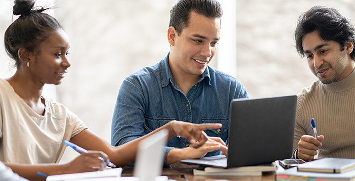 Master's in Computer Science students gather around a laptop