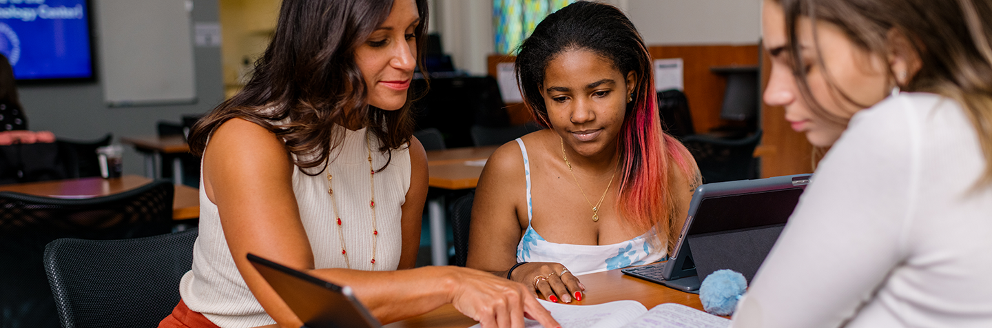 Student in the Curry College Program for Advancement of Learning (PAL) smiles with her professor during a PAL Academics session