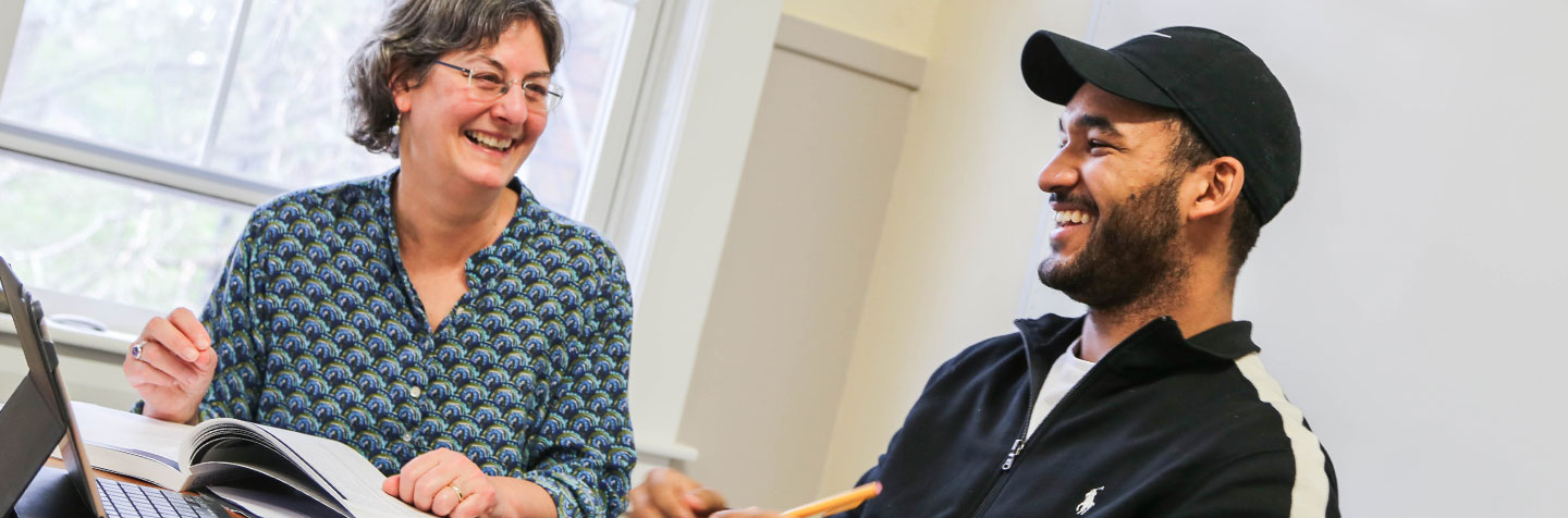 Student in the Curry College Program for Advancement of Learning (PAL) smiles with his professor during a one-on-one PAL Academics session