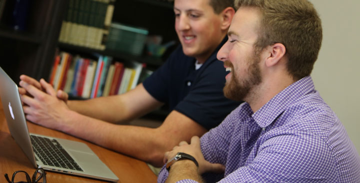 Curry College Program for Advancement of Learning (PAL) students work off a laptop together