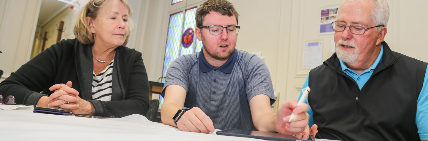 A student works with alumni at the PAL Adult Center at Curry College