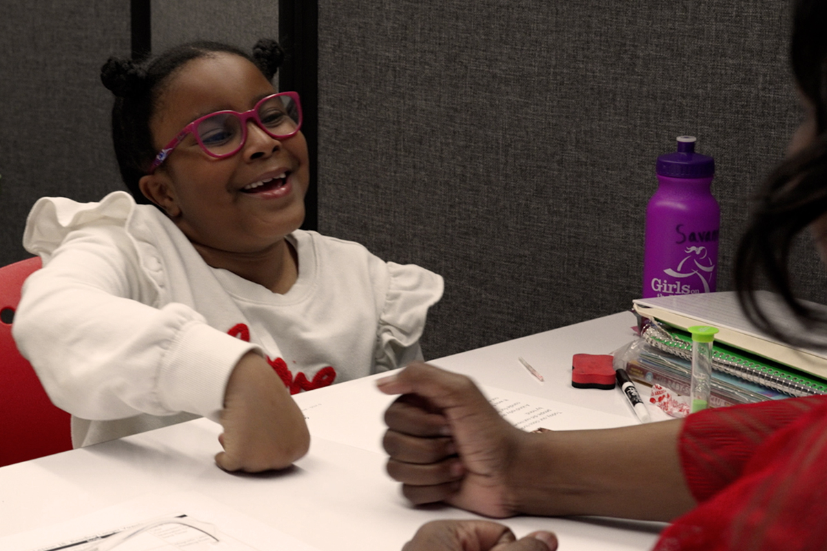 A student smiles while learning at the Aicardi Early Steps program