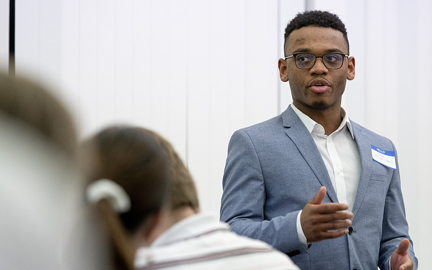 A student in a blue suit gives a presentation