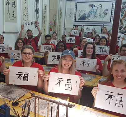 Curry College students hold up their creative writing work in China