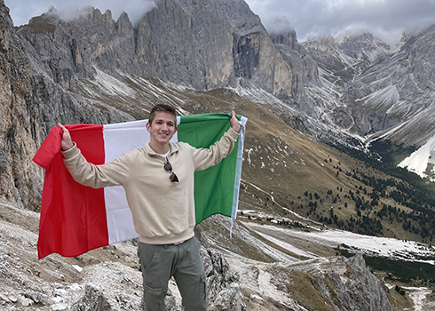 Joey Deprey wrapped in an Italian flag in the mountains of Italy