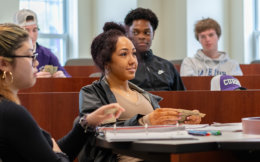 A student learns about currency in a Curry College economics course
