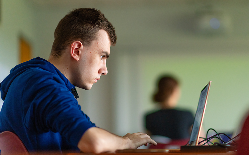 An Entrepreneurship major on his laptop at Curry College