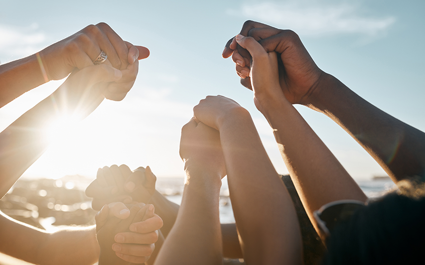 Multiple hands united raised the air representing the Community Advocacy and Justice major at Curry College
