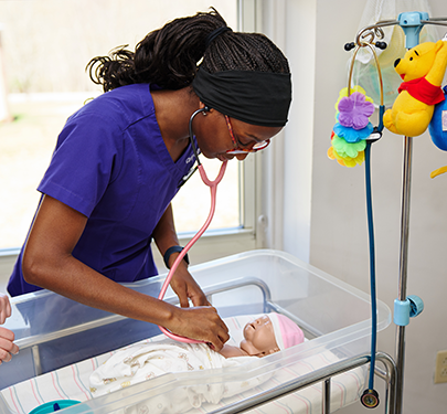 A Curry Nursing student works with a SIM baby in the lab on campus