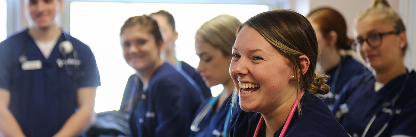 Students at Curry College in the lab smiling while pursuing a Nursing Degree