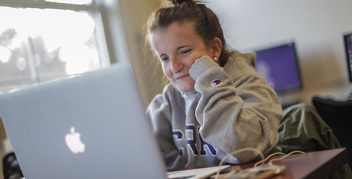 A Curry College writing student at her laptop