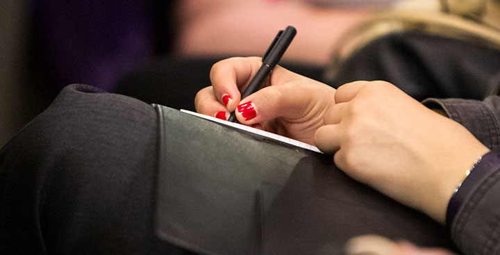 A student writes in a notebook on her lap