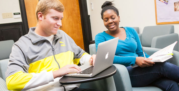 Two students complete a writing assignment on their laptops