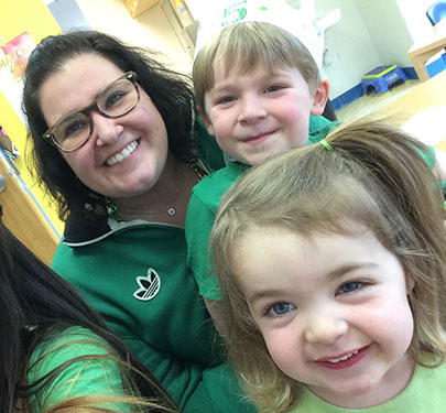 A Curry College CECC teacher poses with two adorable toddlers