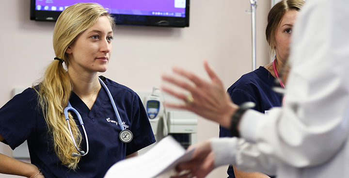 A student listens intently in Nursing lab