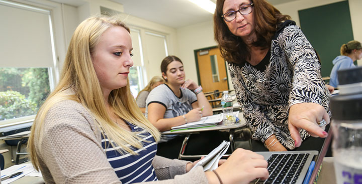 A Curry College professor helps a First-Year student in class